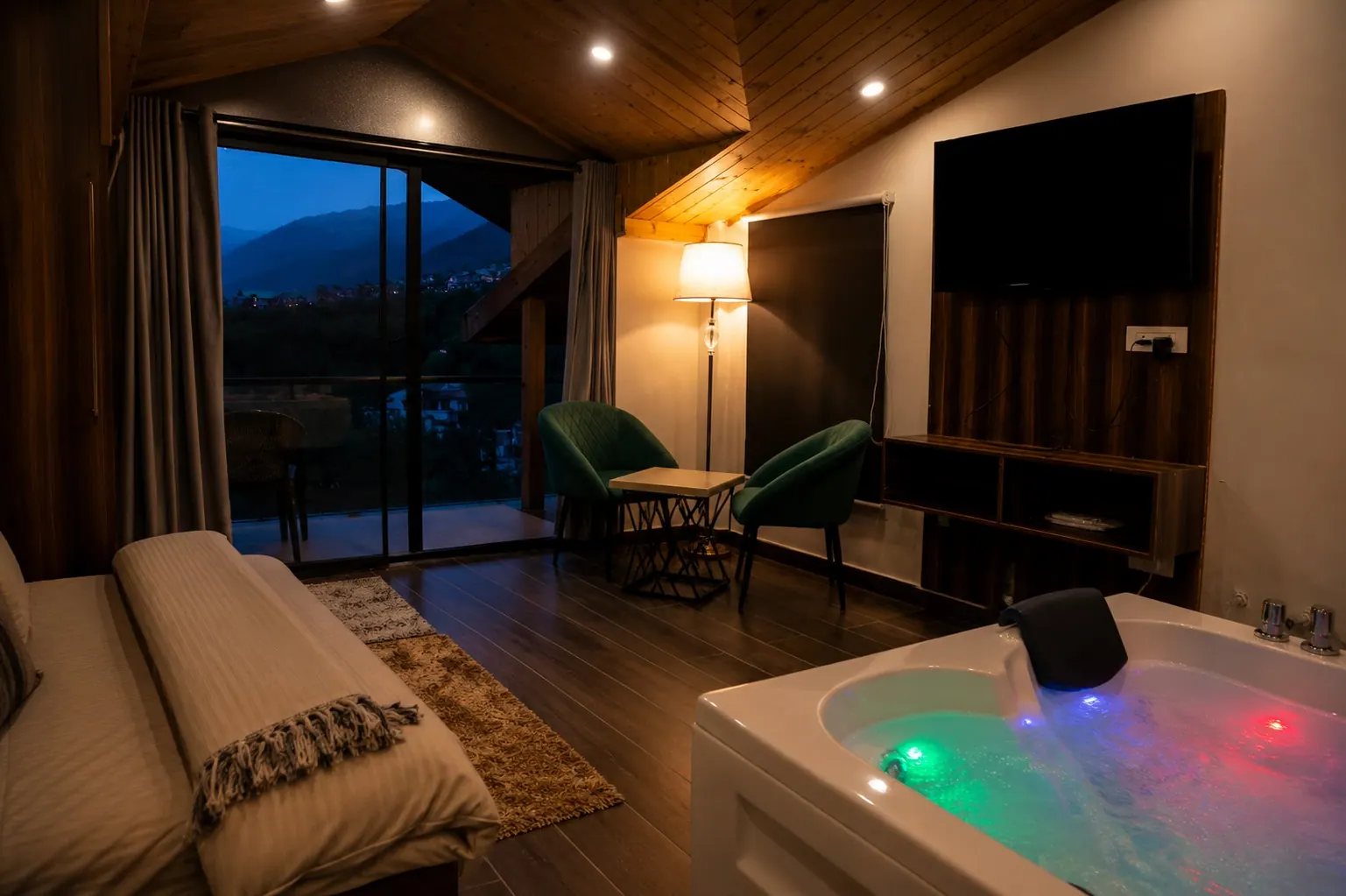 In-room jacuzzi with coloured lights beside a large glass door with a Himalayan mountain view at HOGS Panorama, Manali