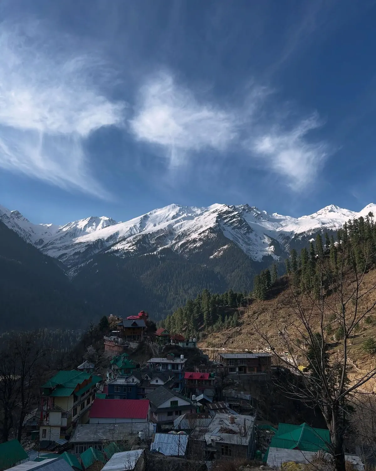 Snow-capped peaks above a Himalayan village of colourful tin roofs in the valley, seen from HOGS Panorama in Manali